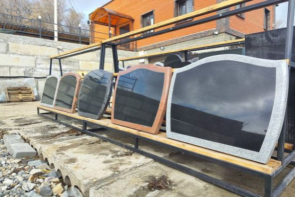 Гранитные памятники разной формы на уличной площадке мастерской